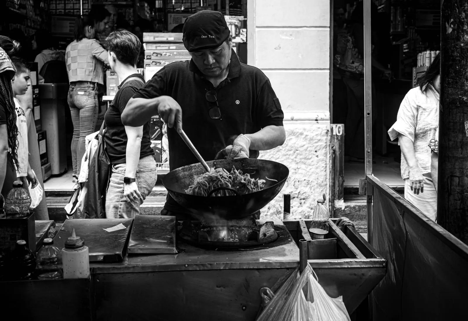 El cocinero saltea en el wok sobre la hornilla de la cocina