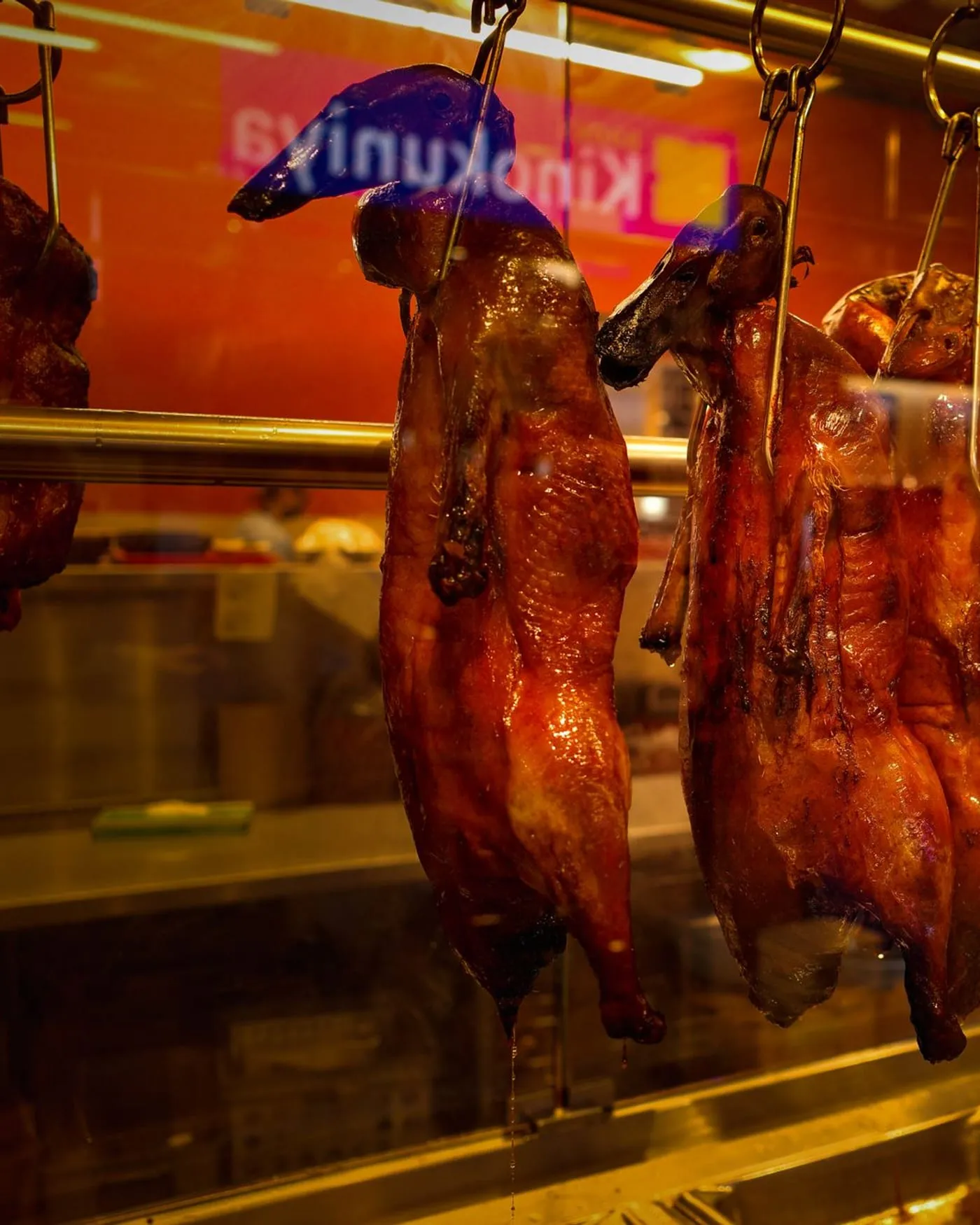 Patos laqueados colgando en la vitrina caliente de la cocina